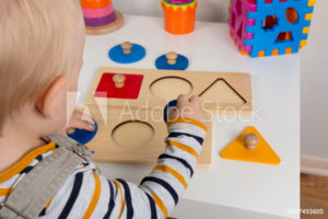 Child works independently with Montessori geometric material for fine motor skills, sensory play. 